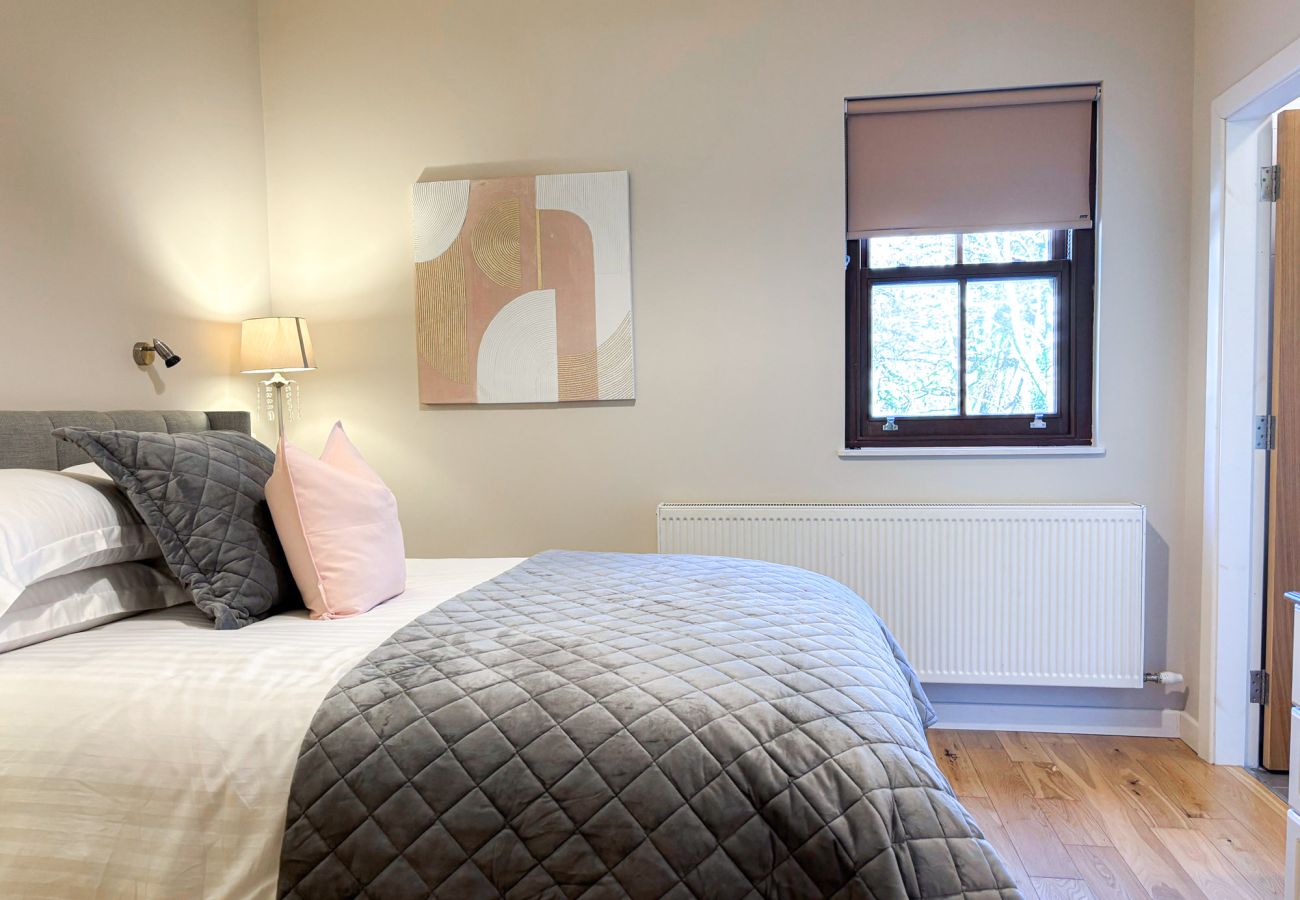 Kylemore Woodland Holiday Cottage. Double bed in bright room , wooden floors, window. 